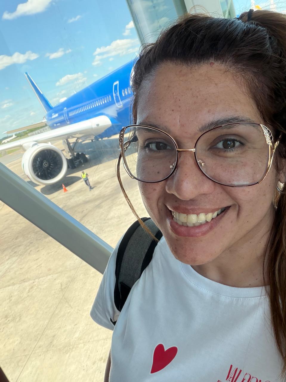 Mey en el aeropuerto, sonriendo frente al avión
